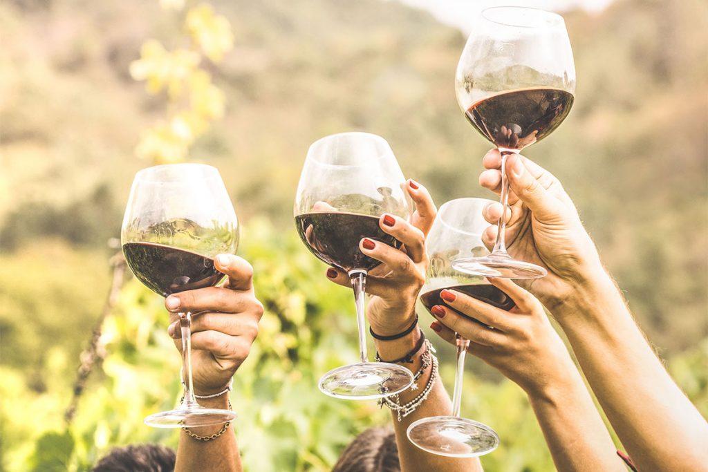 people raising their glasses of wine in the air.