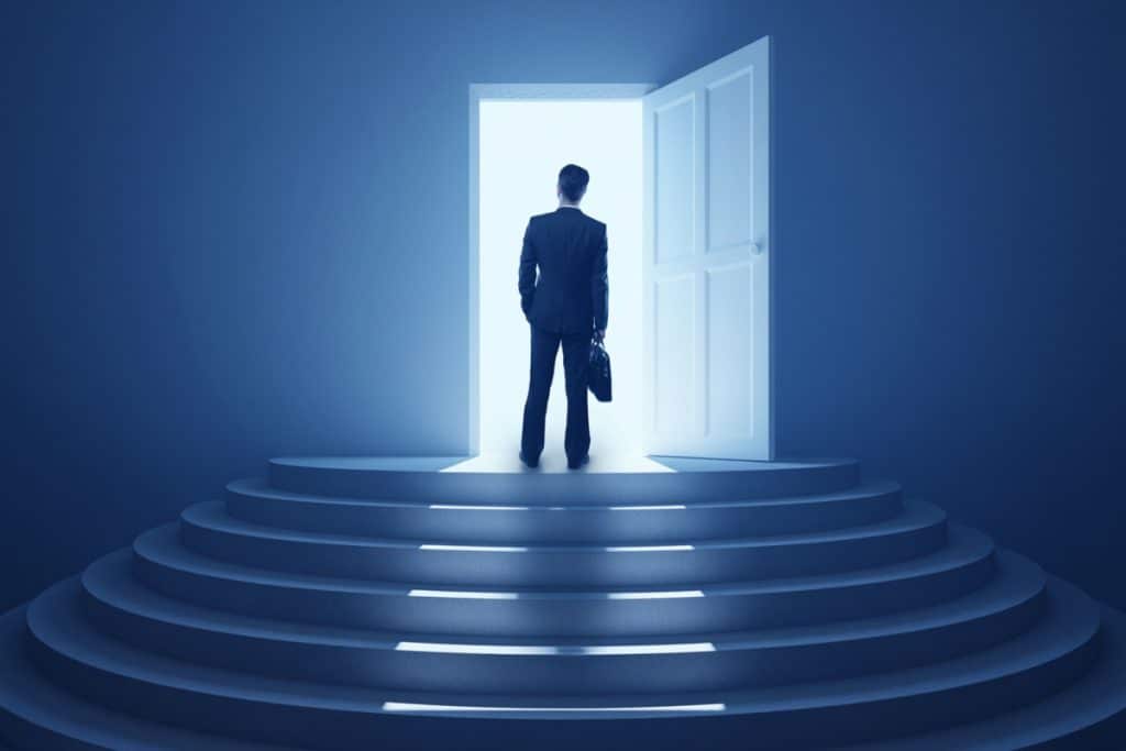 a business owner standing at a doorway with light shining through it illustrating a doorway to success